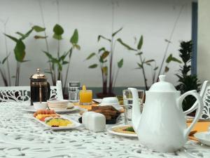 un tavolo con teiera bianca e piatti di cibo di Villa Wodeyarmutt Tropical luxury living a Sringeri