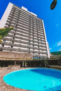 a large building with a large swimming pool in front of it at Ferraretto Guarujá Hotel & Spa in Guarujá