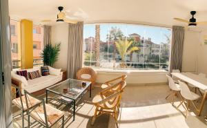 a living room with a couch and chairs and a large window at Sotogrande Alboaire- Waterfront luxury 4 bedroom Apt in the Marina of Sotogrande in Sotogrande