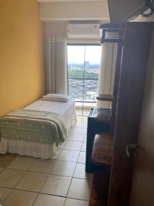 a bedroom with a bed and a large window at Marge Hotel in Aparecida