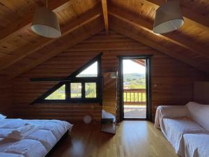 um quarto no sótão com 2 camas e uma grande janela em Chalet Klimatia - Όμορφη ξύλινη μεζονέτα με τζάκι 