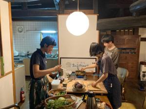 a group of people standing in a kitchen preparing food at 一汁一菜の宿　ちゃぶダイニング Ichiju Issai no Yado Chabu Dining Unforgettable Farmstay experience in Deep Kyoto in Ayabe