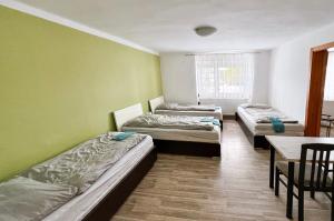 three beds in a room with a table and chairs at Penzion Zahrádka in Lázně Bohdaneč