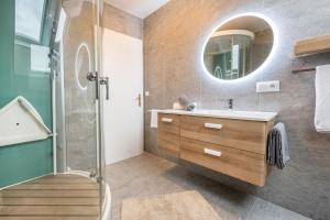 La salle de bains est pourvue d'une douche, d'un lavabo et d'un miroir. dans l'établissement Alpen Living - 2 Stock, à Cadipietra