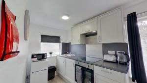 a kitchen with white cabinets and a black counter top at Symons House in Chatham +3 photos