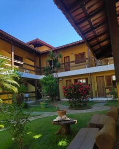 a courtyard of a building with a table in the grass at Pousada Flor de Lotus in Itacaré