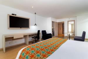 a bedroom with a bed with a desk and a television at Hotel Rosales Plaza in Bogotá
