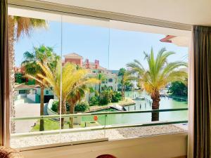 una ventana con vistas al agua y a las palmeras en Sotogrande Alboaire- Waterfront luxury 4 bedroom Apt in the Marina of Sotogrande, en Sotogrande