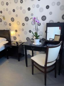 ein Schlafzimmer mit einem Schreibtisch mit einem Spiegel und Blumen an der Wand in der Unterkunft Design-Boutique Hotel Vosteen in Nürnberg