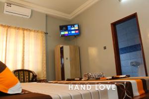 a room with a bed and a tv on the wall at HAND LOVE in Cotonou