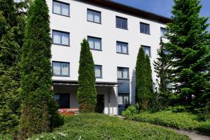 a white building with trees in front of it at Olympia Hotel Suhl in Suhl