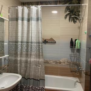 y baño con cortina de ducha, bañera y lavamanos. en Apartment 7 mikro, en Bishkek