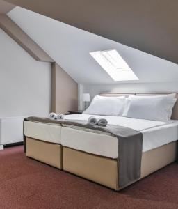 een slaapkamer met een groot bed en een dakraam bij Garni Hotel Aline in Šabac