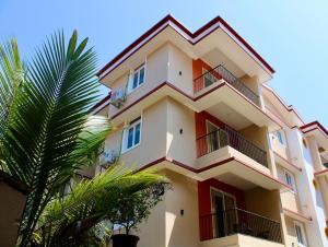 a building with balconies and a palm tree at Kay's Calangute Resort Service Apartments in Calangute
