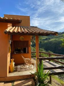 ein Haus mit einem Tisch und einem Stuhl auf einer Terrasse in der Unterkunft Pousada Fecho da Serra in Capitólio