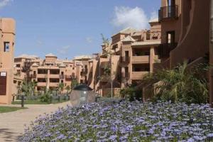 a group of buildings with purple flowers in a courtyard at E2 equipado en Playa Granada con terraza de 11m2 in Motril