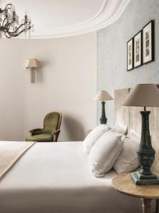 a bedroom with a white bed with a table and a chair at New Hotel Roblin in Paris
