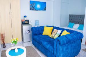 a living room with a blue couch and a bed at LaMeg Furnished Studio in Fedha in Nairobi