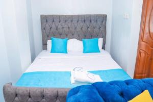 uma cama com lençóis azuis e brancos e almofadas azuis em LaMeg Furnished Studio in Fedha em Nairobi