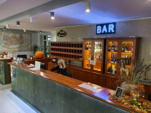 a woman sitting at a bar in a restaurant at Hotel Pietrak in Trzemeszno