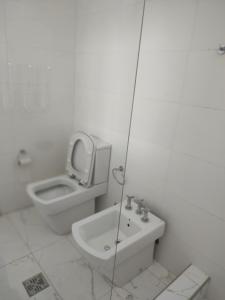 a white bathroom with a toilet and a sink at Caminito Apart in Buenos Aires