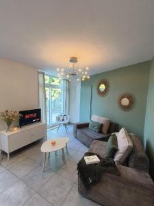 a living room with a couch and a tv at Chez Emma et Louise - Maison individuelle avec stationnement in Mâcon