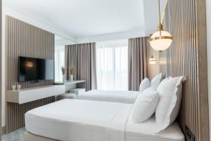 ein Hotelzimmer mit 2 Betten und einem TV in der Unterkunft Bodrum Astrid Hotel in Gümüşlük