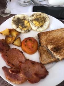 a plate of breakfast food with eggs bacon and toast at LEHAE BNB in Mbabat