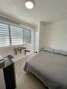 a bedroom with a bed and a table and windows at Casa Magdalena in San Juan