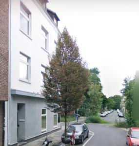 un coche estacionado junto a un árbol al lado de un edificio en RAJ Living - 1 or 3 Room Apartments - 30 Min Messe DUS, en Duisburg