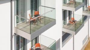 - un bâtiment avec des balcons en verre, une table et des chaises dans l'établissement Lodges Hotel Morges, à Morges