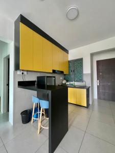 a kitchen with yellow cabinets and a counter with stools at Meritus Studio Holiday (Perai) in Perai