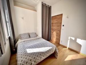 um pequeno quarto com uma cama e uma porta de madeira em Maison de ville tout confort à Cannes et à 10 Minutes à pied de la plage em Cannes