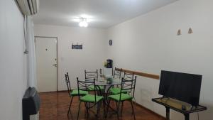 a dining room with a table with chairs and a television at Departamento frente a Plaza España in Mendoza