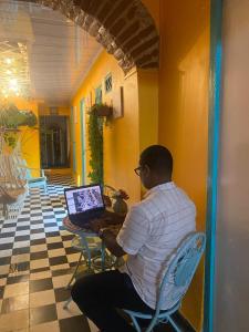 un uomo seduto a un tavolo con un portatile di Casa Renacer a Cartagena de Indias