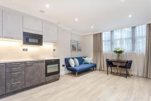 uma cozinha com um sofá azul e uma mesa em Cleveland Residences Farringdon em Londres