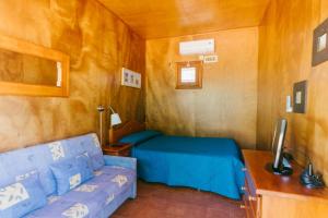 Habitación pequeña con cama y sofá en Camping Playa La Bota, en Punta Umbría
