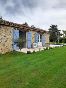 uma casa de pedra com portas azuis e um quintal em La petite maison bleue avec piscine em Loubejac