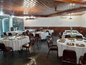 ein großes Zimmer mit Tischen und Stühlen mit weißen Tischdecken in der Unterkunft Vitória Palace Hotel in Lavras