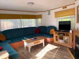a living room with a blue couch and a tv at Shambala Country Cabin in Kentisbeare