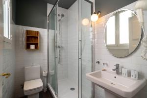 La salle de bains est pourvue d'une douche, d'un lavabo et d'un miroir. dans l'établissement Casa Gracia Apartments, à Barcelone