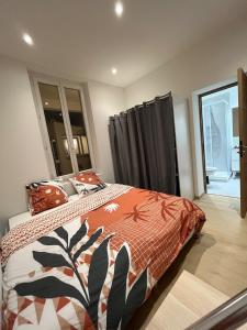 a bedroom with a bed with an orange comforter at Maison de ville tout confort à Cannes et à 10 Minutes à pied de la plage in Cannes