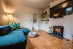 a living room with a blue couch and a fireplace at The Limes Benhall - Air Manage Suffolk in Saxmundham