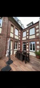 a patio with a table and an umbrella in front of a brick building at La marine 2 in Deauville