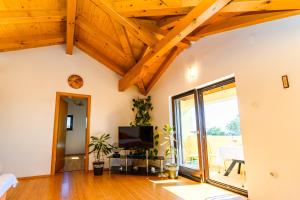 a living room with wooden ceilings and a flat screen tv at Apartman Marina in Martinšćica