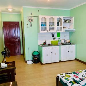 a kitchen with white cabinets and a red door at Albergo Hotel - Studio Condo Unit - Baguio Transient in Baguio