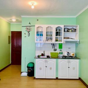 - une cuisine avec des murs verts et des placards blancs dans l'établissement Albergo Hotel - Studio Condo Unit - Baguio Transient, à Baguio