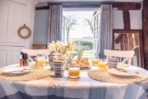 a table with plates and glasses of orange juice at Rose Cottage in Lavenham in Lavenham