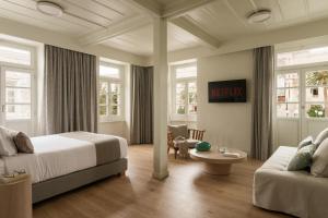 Habitación de hotel con cama y sofá en SYROS SOUL LUXURY SUITES, en Ermoupoli