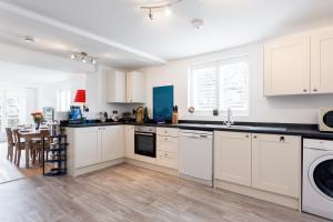 a white kitchen with white cabinets and a table at The Old Butcher's Cottage in Corfe Castle